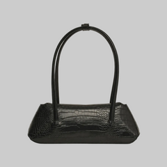 A black crocodile-embossed leather handbag with a unique double-loop top handle, shown against a neutral light gray background.