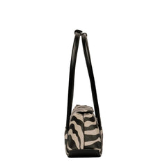 A small shoulder bag with a black and beige zebra print body and solid black straps, shown from the back against a plain light beige background.